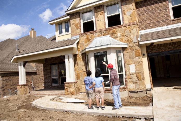 Builder meeting with woman and daughter at new home construction