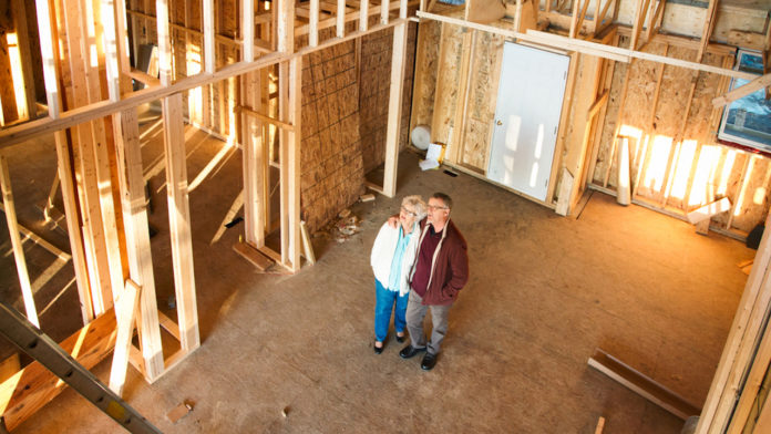 Senior couple visiting construction site of new home 55+ housing market