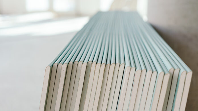 Large stack of white chip board against a wall gypsum
